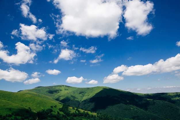 White clouds over green mountains. Summer mountains landscape for wallpaper