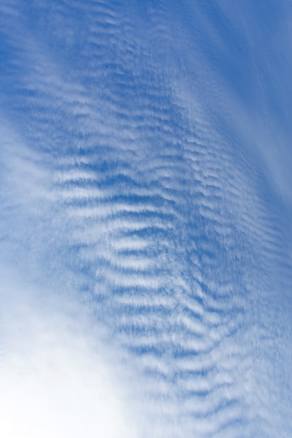 水色の空を背景に海の波のような白い雲。