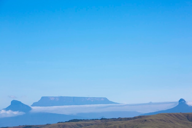 Photo white clouds over the mountains with clear blue sky