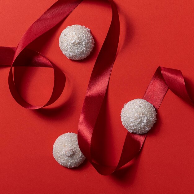 White coconut cookies on a red ribbon on a red background