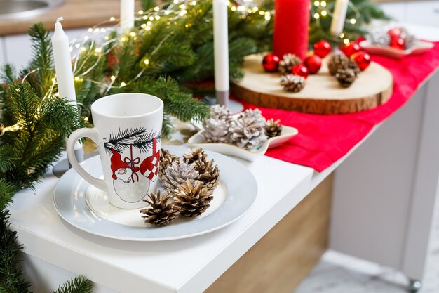 White coffee cup on the kitchen table against the background of Christmas decorations. Lumps on a platter