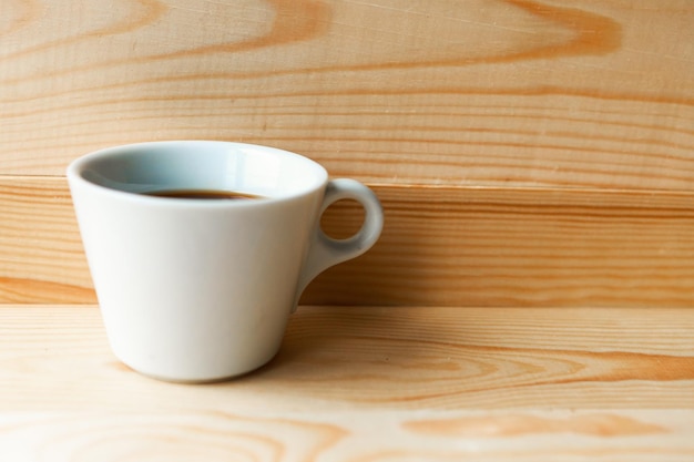 Белая кофейная чашка на деревянном фоне