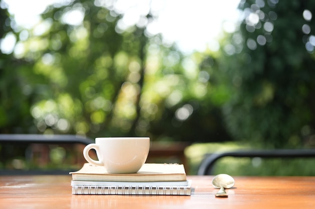 White coffee cup on wooden table with notebooks ans spoon on wooden table