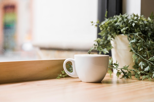 Tazza di caffè bianco sul ripiano del tavolo in legno