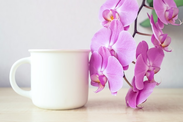 White coffee mug mockup with flowers lilac orchid closeup