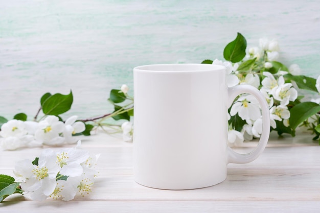 Foto mockup di tazza da caffè bianca con teneri fiori di melo tazza vuota mock up per modello in stile promozione del design