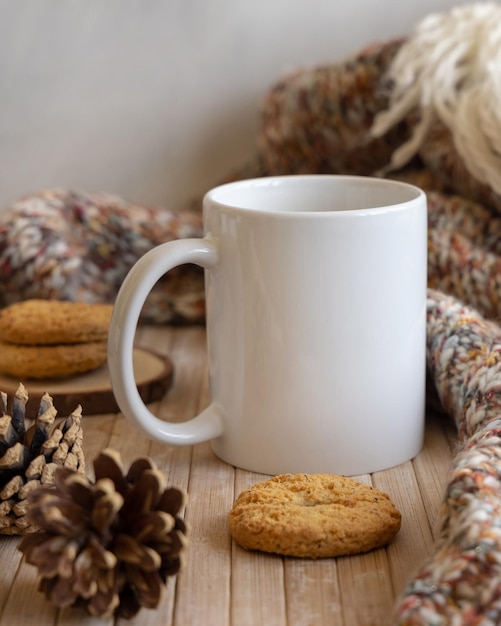 white coffee mug near pine cones cookies and knitted sweater on wooden table close up copy space winter christmas mock up bohemian ethnic or scandinavian style