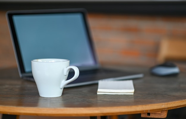 White coffee mug on the table with laptop.