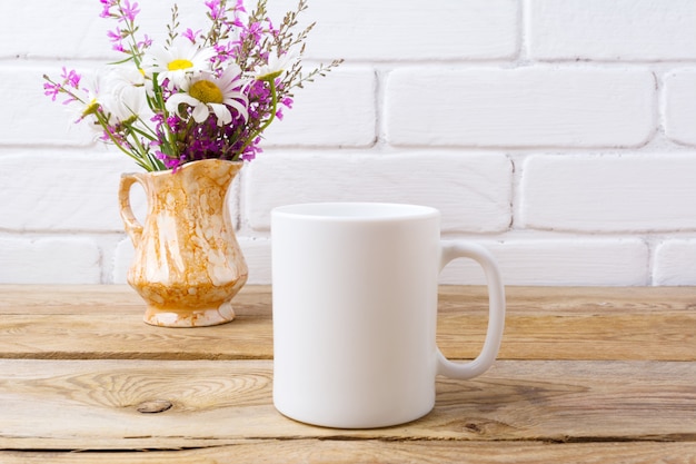写真 ゴールデンピッチャーにカモミールと紫の花と白いコーヒーのマグカップ