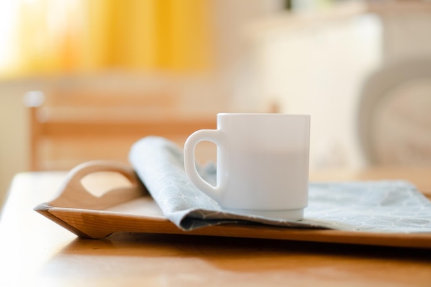 white coffee mug with napkin on table in real kitchen interior with bright natural sunlight
