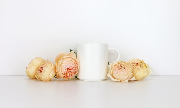 Foto tazza da caffè bianco con rose. tazza vuota mock up per la promozione del design.