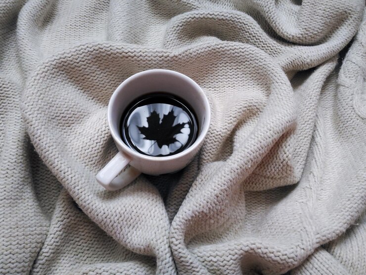 Photo 白色的咖啡杯,杯子上有叶的反射,在色针织背景上