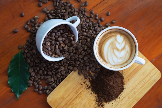 White coffee mugs and coffee beans Poured on a wooden table