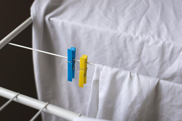 White color. Clothespins on the dryer. Things dry after washing. Fresh smell. Clean linen.