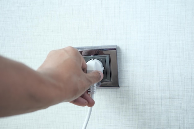 White color power cord cable plugged into wall