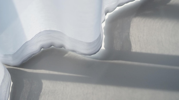 Прозрачный воздушный занавес белого цвета, раскачивающийся от дуновения ветра и белой напольной плитки