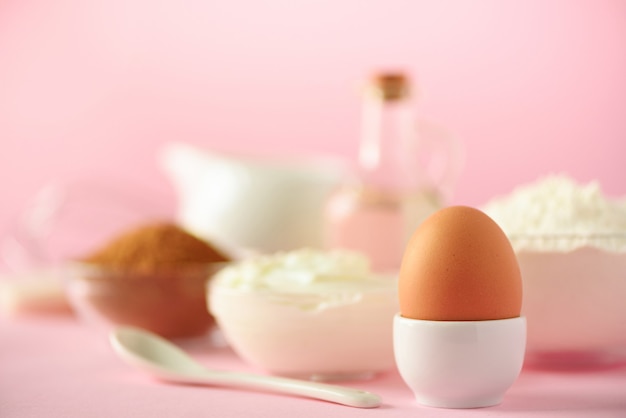 White cooking utensils on pink background. Food ingredients. Macro of egg. Cooking cakes and baking bread concept. Copy space.