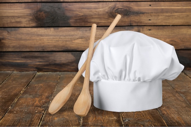 Foto cappello da cuoco bianco e cucchiai di legno sul tavolo di legno