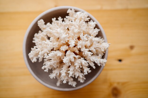 White coral in a cup on a wooden background.