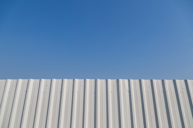 White corrugated metal fence with blue sky background