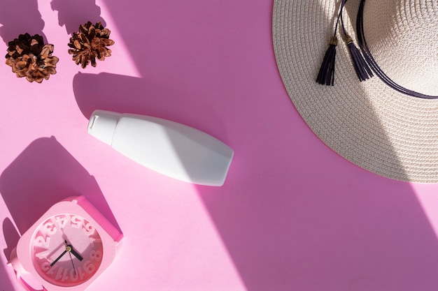 White cosmetic bottle container with pine tree flower and white cap on pink paper background. Natural organic beauty product concept, minimalist style