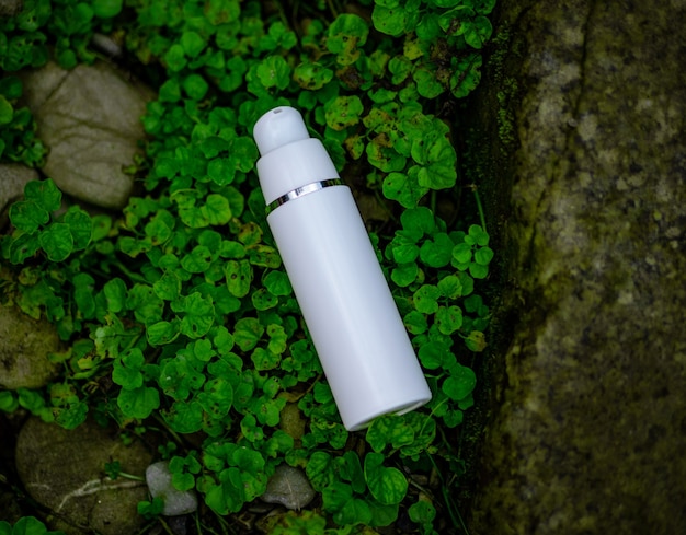 A white cosmetic bottle lies on the grass. Natural composition