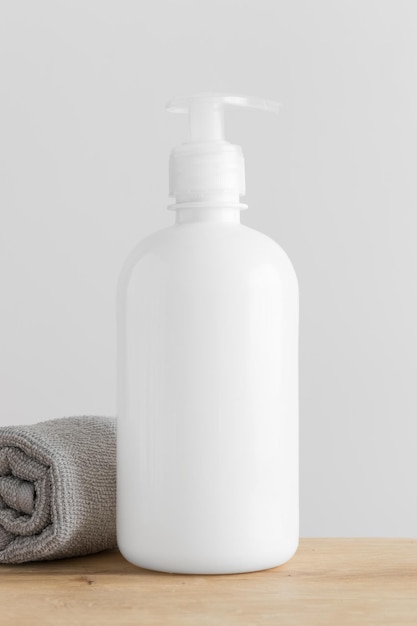 White cosmetic bottle mockup with a towel on a wooden table