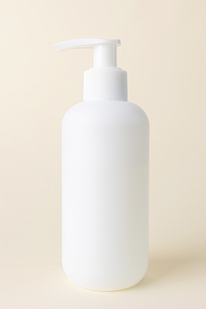 Photo white cosmetic bottle with dispenser without a label on beige