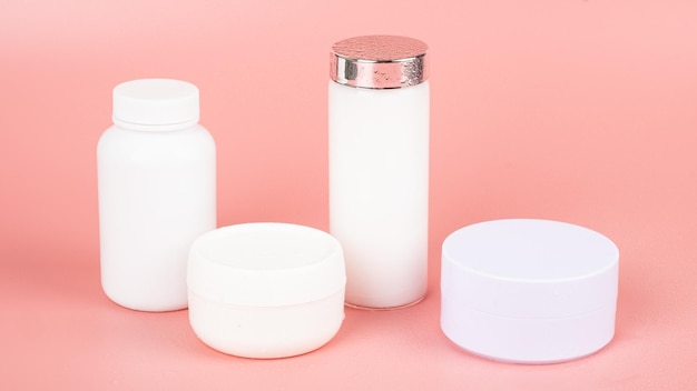 White cosmetic bottles on pink background beauty skin care