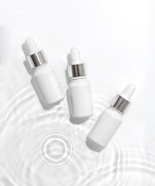 White cosmetic bottles on the water surface. Summer water pool fresh concept. Flat lay, top view.