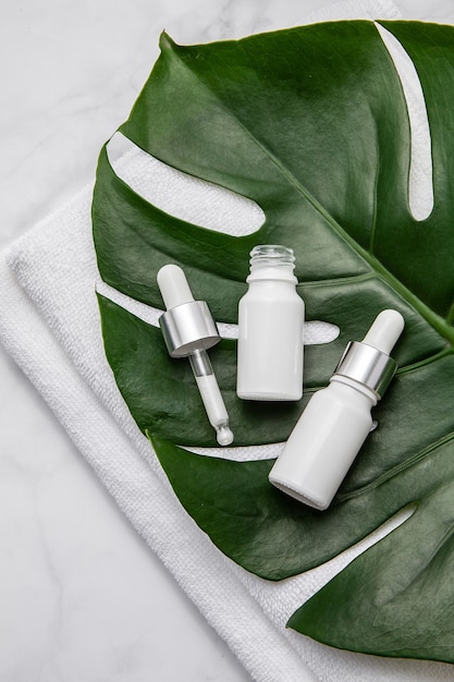 White cosmetic bottles with green leaves on white