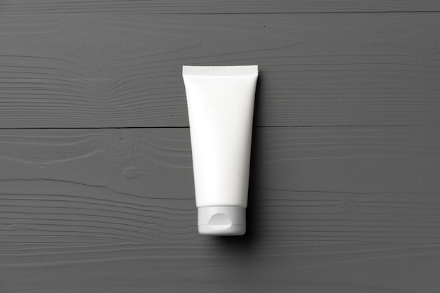 White cosmetic container on gray wooden background top view