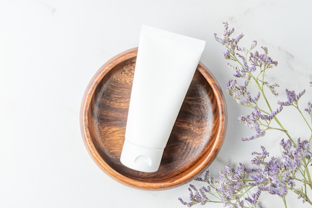 White cosmetic cream tube balm jar mockup in wooden bowl on white marble background Make up product blank container Body and face care