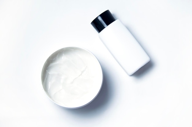 Crema cosmetica bianca su fondo bianco e bolla bianca con coperchio nero