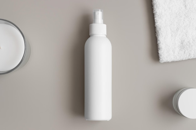 White cosmetic spray bottle mockup with a towel on the beige table