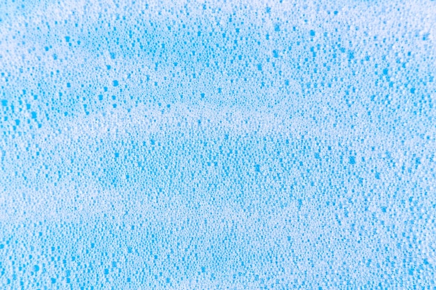 White cosmetics foam texture on blue backdrop Cleanser soap shampoo bubbles Foamy skin care