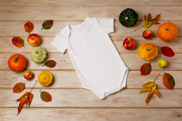 White cotton baby short sleeve onesie mockup with fall leaves apples yellow red and green pumpkins