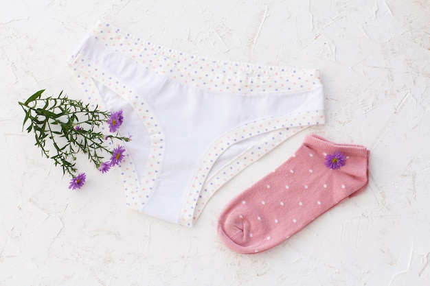 Mutandine di cotone bianco con fiori e calze rosa da donna sulla superficie strutturata bianca