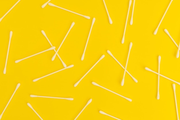 White cotton swabs on a bright yellow background