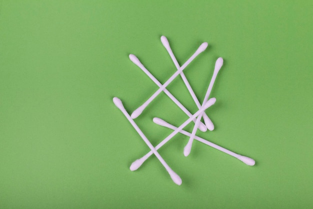 White cotton swabs on green background