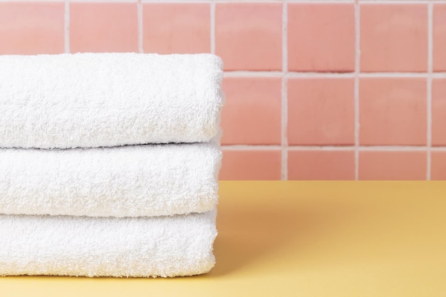 White cotton towels on table inside a bathroom wall tiles ceramic background Copy space