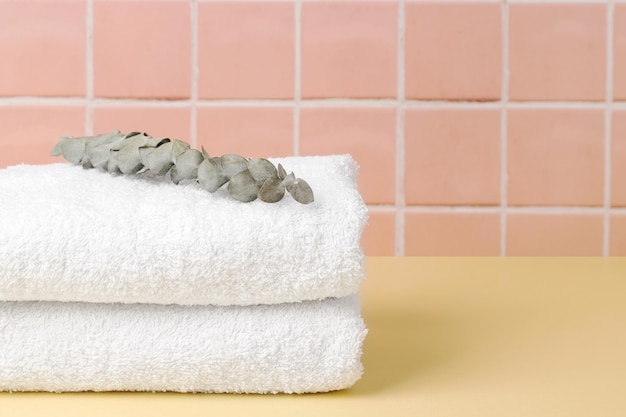 White cotton towels on table inside a bathroom wall tiles ceramic background Copy space