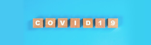 正方形の木製ブロックに白い「COVID19」のテキスト