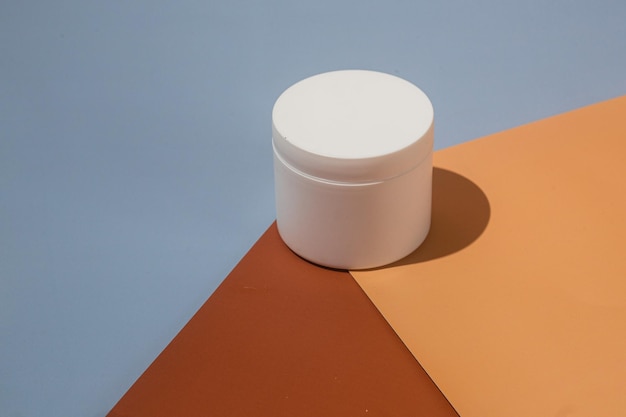 white cream jar isolated on a colorful geometric background