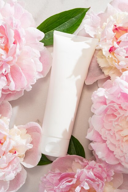 white cream tube in soft morning light styled with fresh peony blooms clean luxurious skincare still life for beauty branding and product campaigns