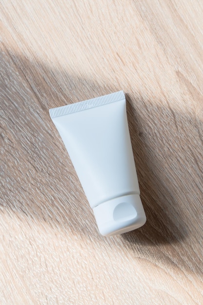 White cream tube on wooden table mockup beauty and care product packaging template