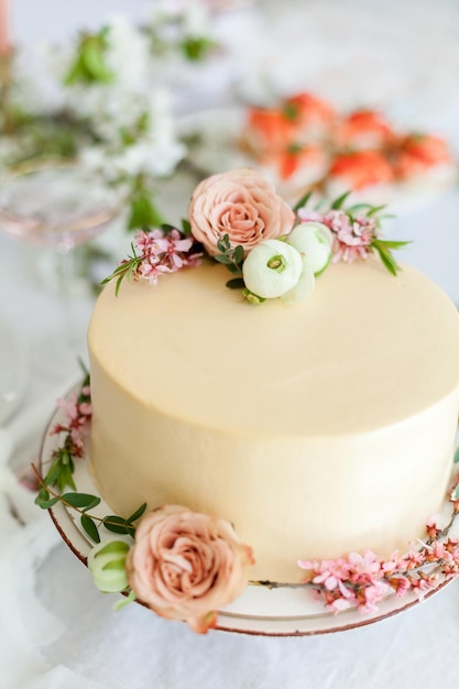 White cream wedding cake decorated with flowers and blooming\
branches