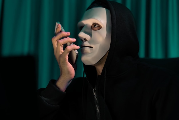 Фото Белая преступная анонимная маска звонит владельцу ит, чтобы угрожать выкупом.