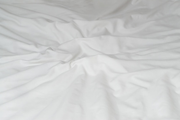 White crumpled or wrinkled bedding sheet or blanket with pattern after guest's use taken in hotel resort room with copy space Untidy blanket background texture