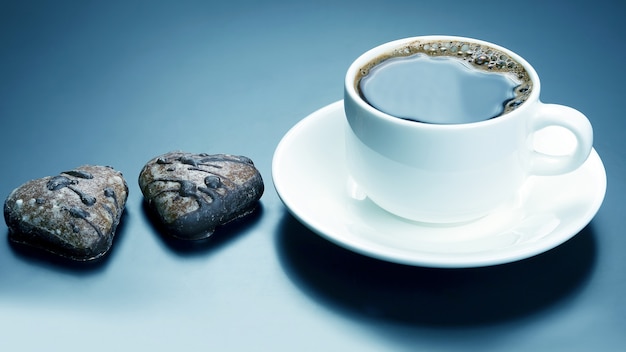 Tazza bianca di caffè nero con cuore di biscotti. cibo da dessert